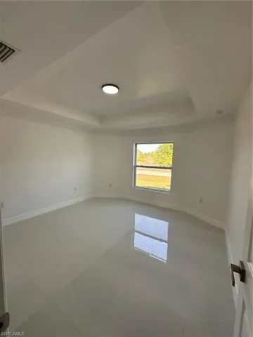 Tiled spare room with a tray ceiling