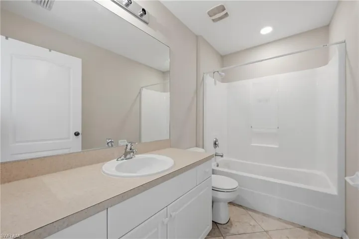 Full bath with tub / shower combination, vanity, and light tile patterned flooring