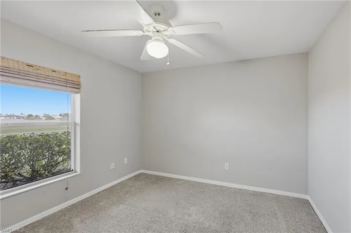 Carpeted spare room featuring baseboards and a ceiling fan