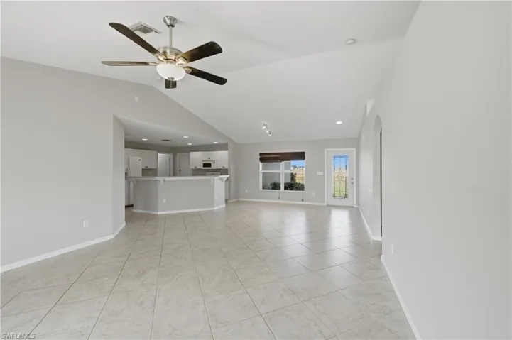Unfurnished living room with vaulted ceiling, recessed lighting, a ceiling fan, arched walkways, and light tile patterned floors