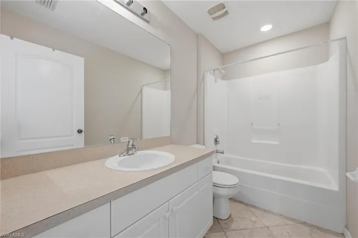 Full bath featuring bathing tub / shower combination, vanity, and light tile patterned flooring