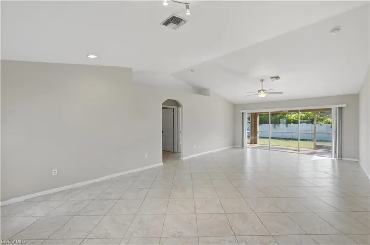 Spare room with arched walkways, a ceiling fan, lofted ceiling, and light tile patterned flooring
