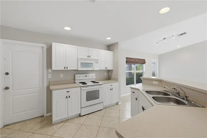 Kitchen with white appliances, recessed lighting, light countertops, white cabinetry, and light tile patterned flooring