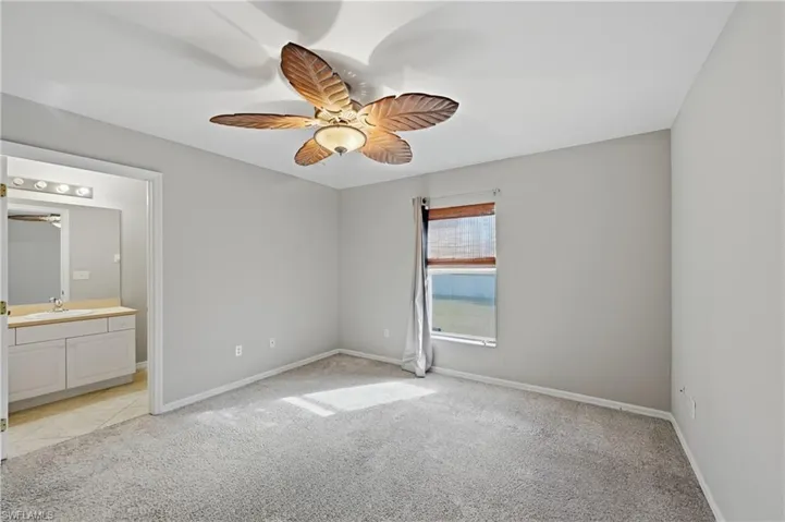 Unfurnished bedroom with light colored carpet, a ceiling fan, and ensuite bath