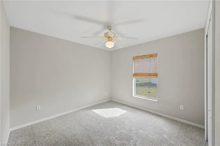Carpeted empty room with baseboards and ceiling fan