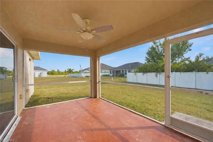 Unfurnished sunroom featuring ceiling fan and a residential view