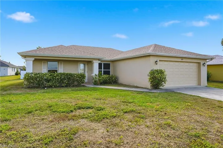 Ranch-style home with stucco siding, a front yard, concrete driveway, and a garage