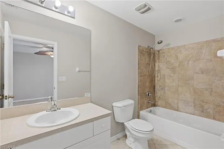 Full bathroom featuring washtub / shower combination, vanity, and light tile patterned flooring