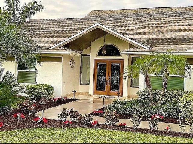 View of exterior entry featuring french doors, stucco siding, and a shingled roof
