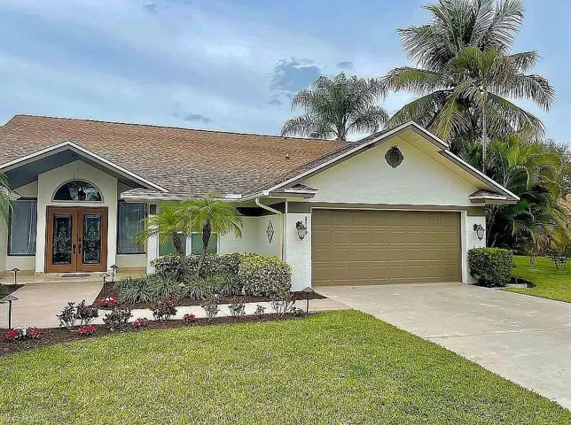 Ranch-style home featuring a garage, concrete driveway, french doors, a front lawn, and stucco siding