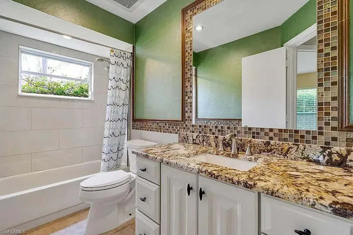 Bathroom with vanity, shower / bath combination with curtain, toilet, visible vents, and decorative backsplash
