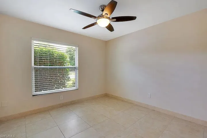 Unfurnished room featuring ceiling fan, light tile patterned flooring, and baseboards
