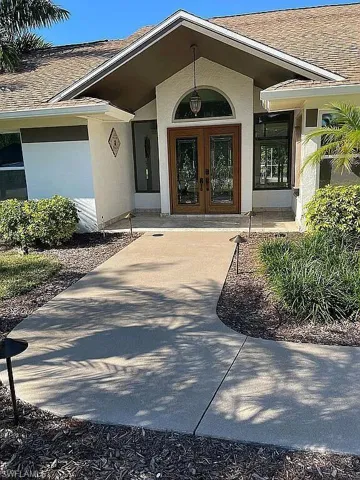 Property entrance featuring french doors, a shingled roof, and stucco siding