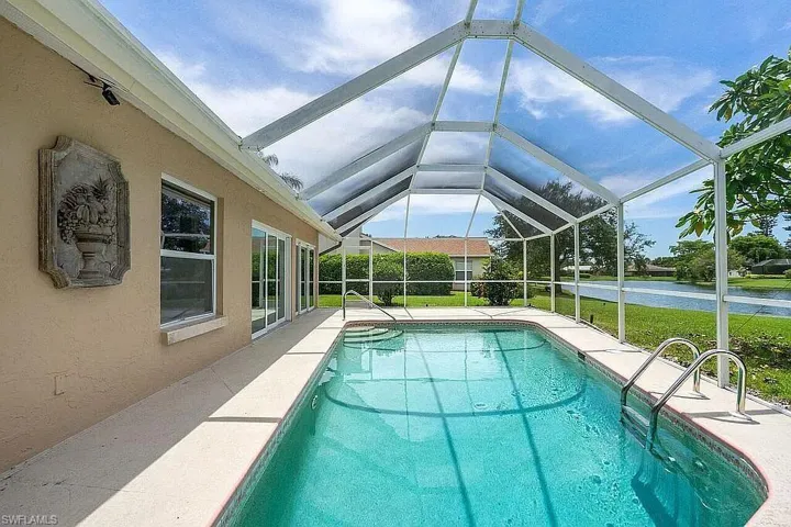 Outdoor pool featuring a water view, a patio, and glass enclosure