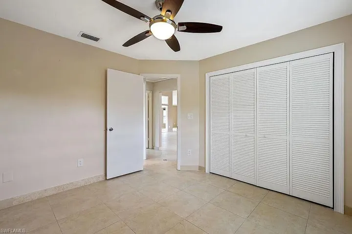 Unfurnished bedroom with visible vents, baseboards, a closet, ceiling fan, and light tile patterned flooring