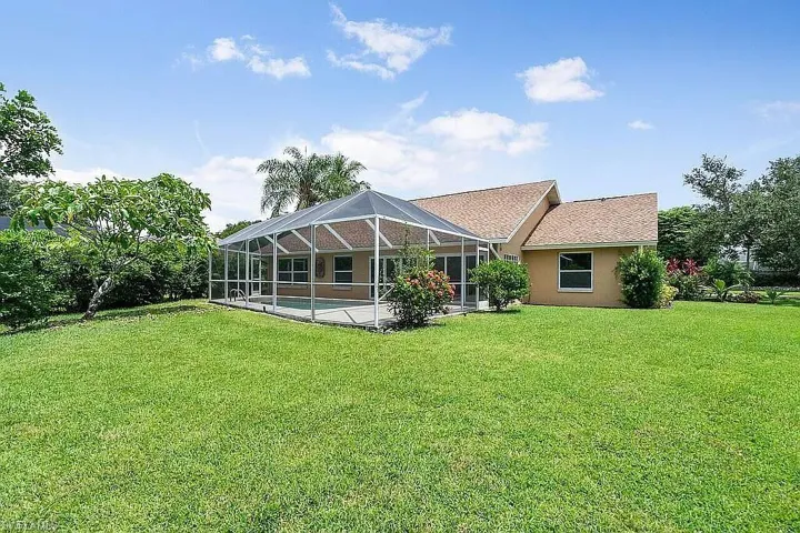 Rear view of property with an outdoor pool, stucco siding, a lawn, a patio area, and a lanai