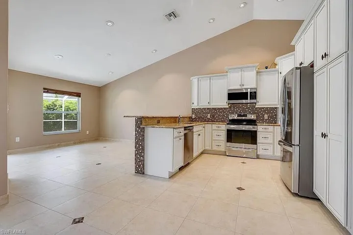 Kitchen with light tile patterned floors, tasteful backsplash, a peninsula, visible vents, and stainless steel appliances