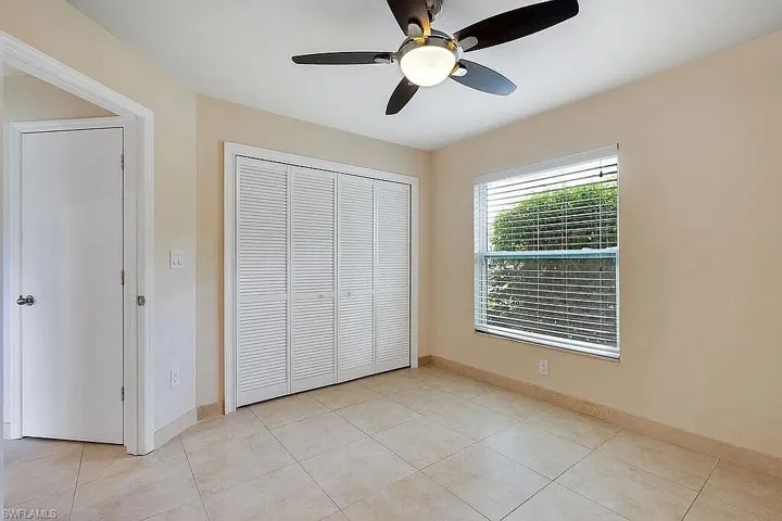 Unfurnished bedroom with a closet, baseboards, a ceiling fan, and light tile patterned floors