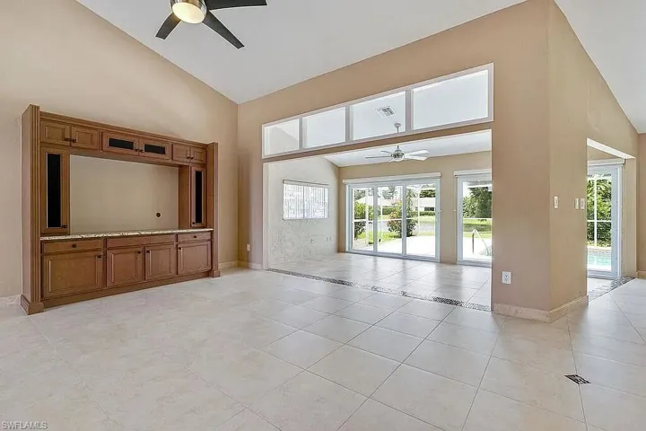 Unfurnished living room featuring high vaulted ceiling, light tile patterned floors, baseboards, and ceiling fan