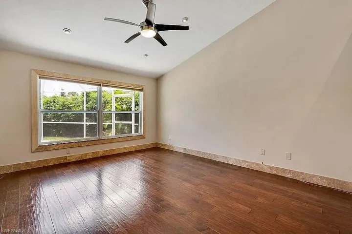 Spare room featuring ceiling fan, baseboards, dark wood-style floors, and vaulted ceiling