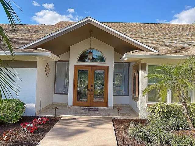 View of exterior entry featuring french doors, a shingled roof, and stucco siding
