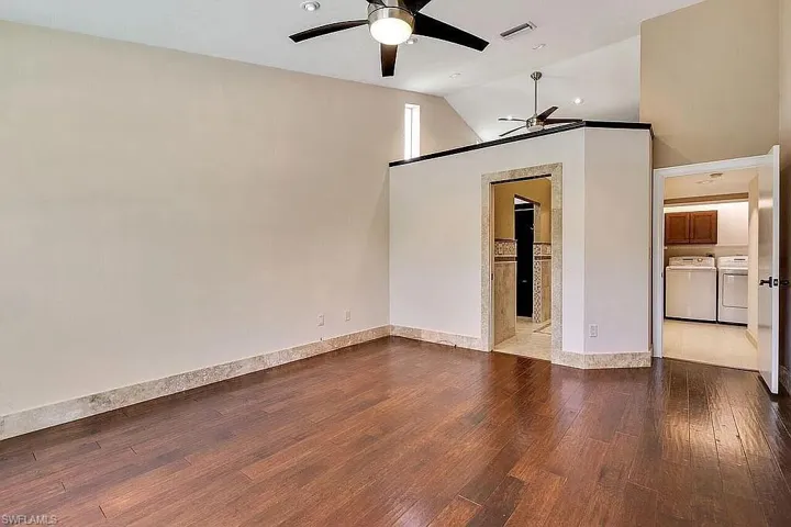 Empty room with washer and dryer, wood finished floors, a ceiling fan, and visible vents