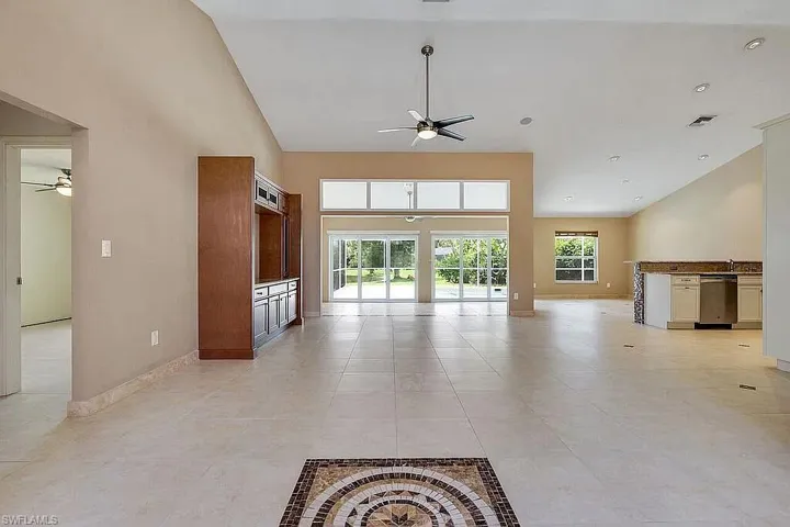 Unfurnished living room with visible vents, ceiling fan, and high vaulted ceiling