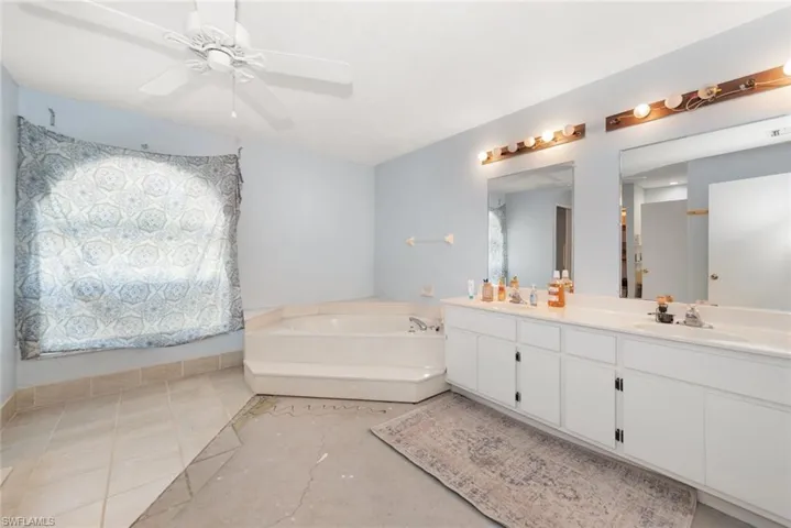 Bathroom featuring double vanity, a bath, and ceiling fan
