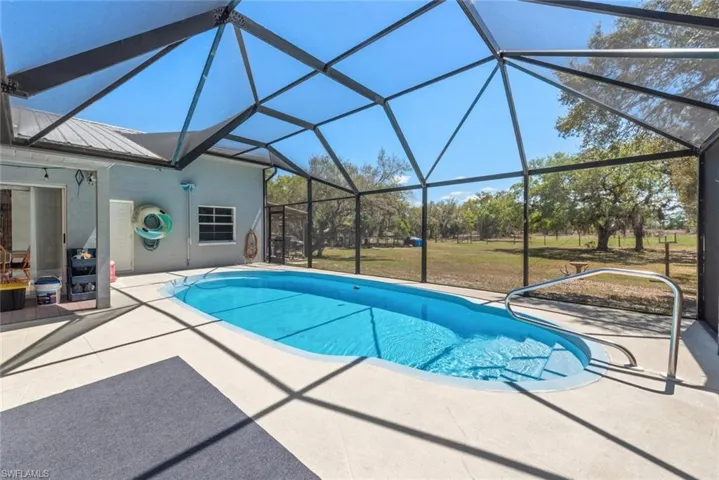 Swimming pool featuring a sunroom, a patio, a lawn, and a lanai