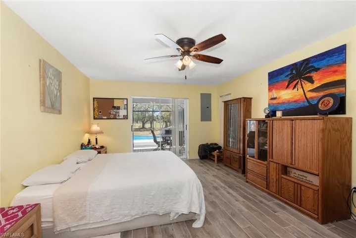 Bedroom featuring wood finished floors, access to outside, ceiling fan, and electric panel