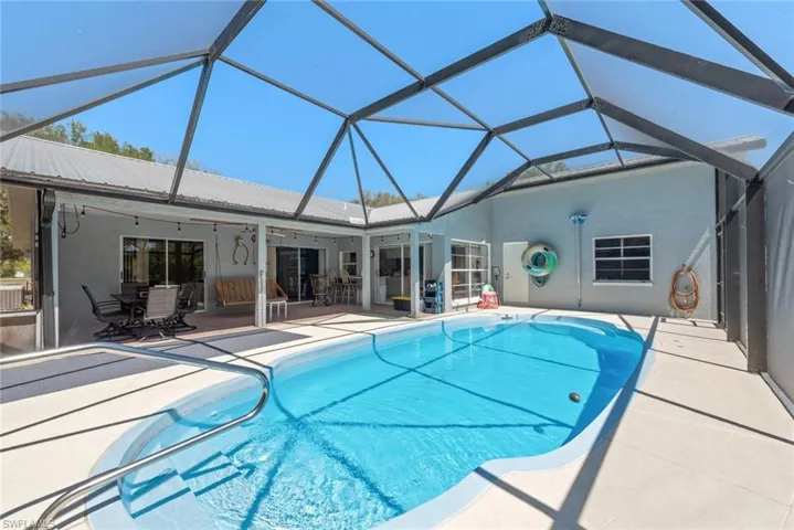 Swimming pool with a sunroom, outdoor dining area, a patio area, and a lanai