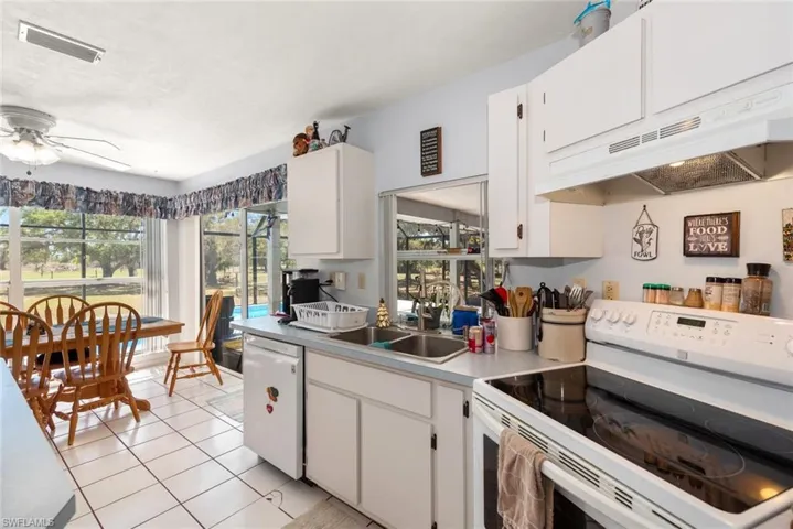 Kitchen with white appliances, white cabinets, a ceiling fan, light countertops, and light tile patterned floors