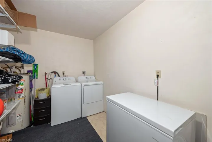 Laundry area with light floors, electric water heater, and independent washer and dryer