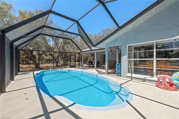 Outdoor pool featuring a patio area, a sunroom, and glass enclosure