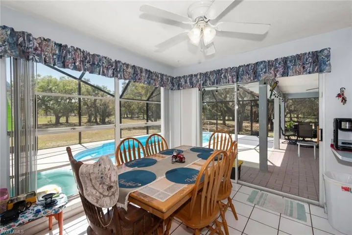 Dining space featuring a sunroom, light tile patterned flooring, and a ceiling fan