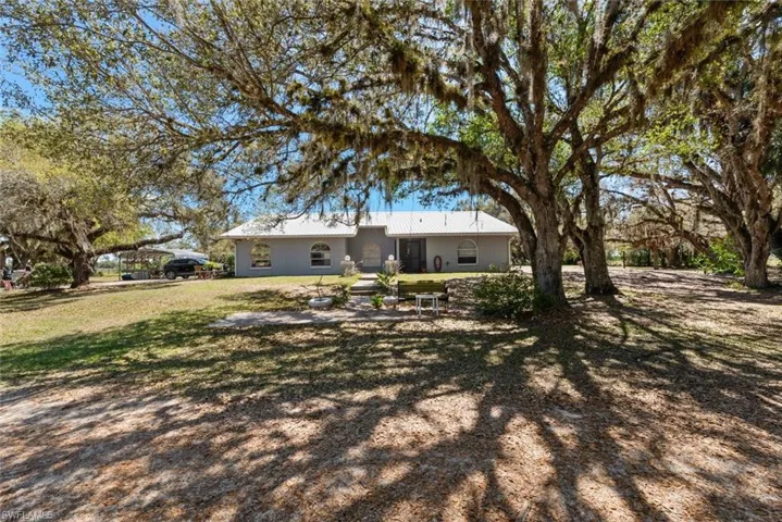 Back of house with a metal roof and a lawn