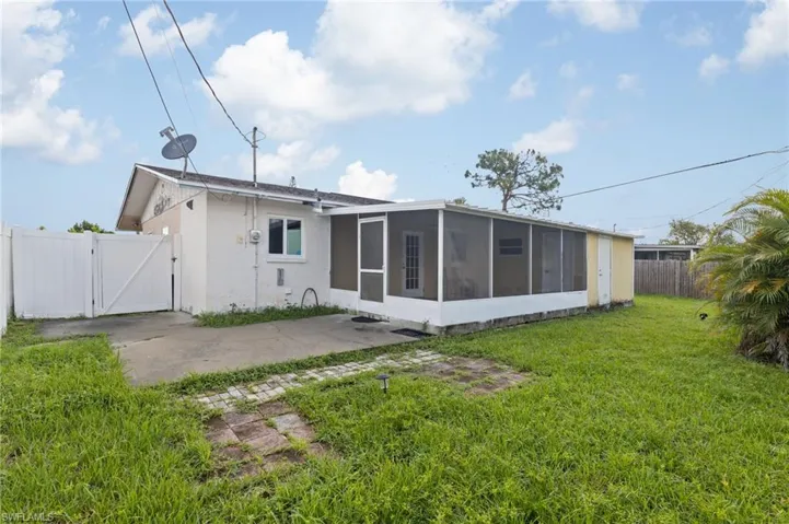 Rear view of house featuring a lawn and a sunroom