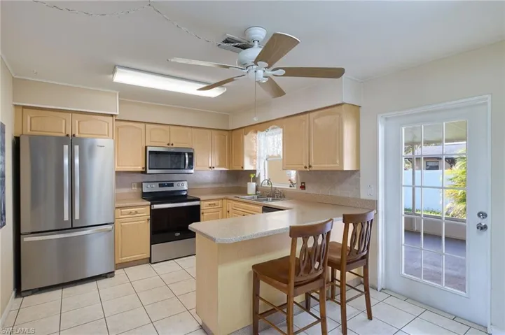 Kitchen with ceiling fan, kitchen peninsula, backsplash, new stainless steel appliances, and sink
