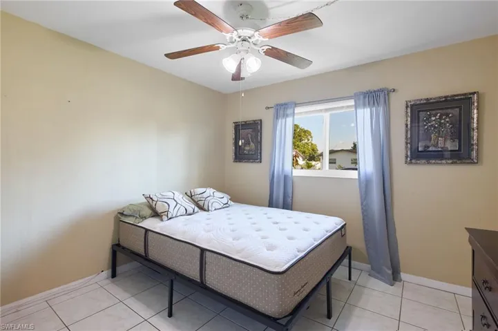 Tiled bedroom featuring ceiling fan