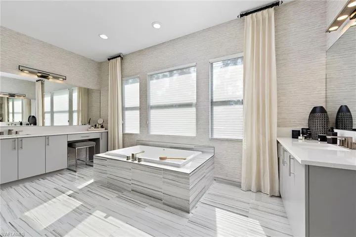 Bathroom with tile patterned floors, a bathing tub, vanity, and tile walls