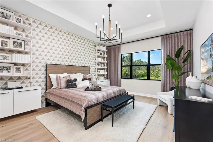 Bedroom with light hardwood / wood-style floors, a raised ceiling, and a chandelier