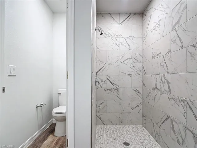 Bathroom with a shower stall and wood finished floors