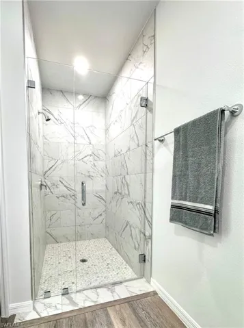 Full bath featuring a marble finish shower and wood finished floors