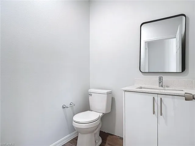 Half bathroom featuring vanity and dark wood-style flooring