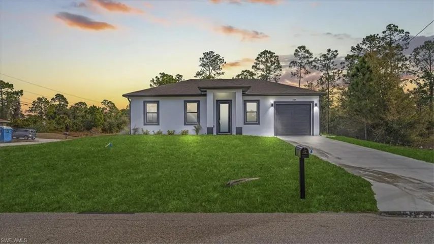 Prairie-style home with driveway, a garage, stucco siding, and a front lawn