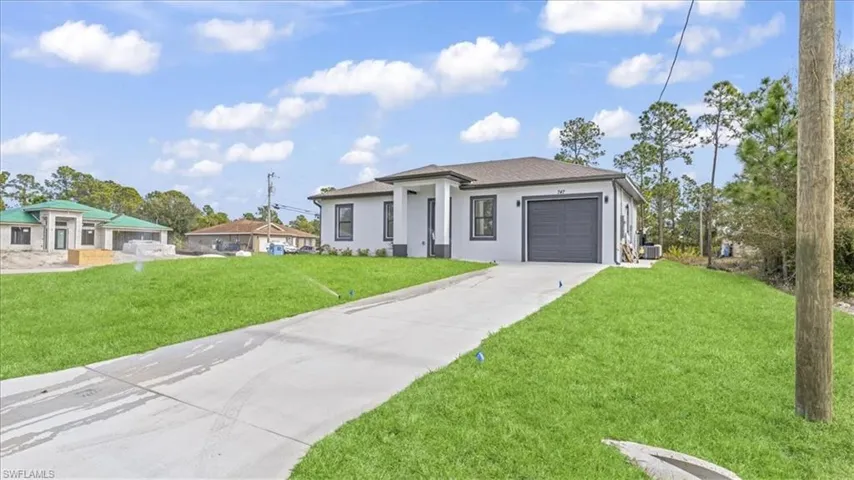 Prairie-style home featuring concrete driveway, a front lawn, stucco siding, and a garage