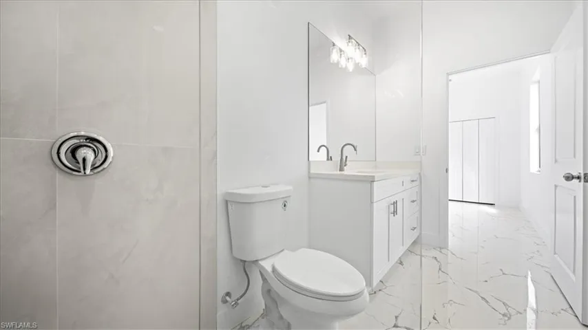 Full bath with vanity, a tile shower, and light marble finish flooring