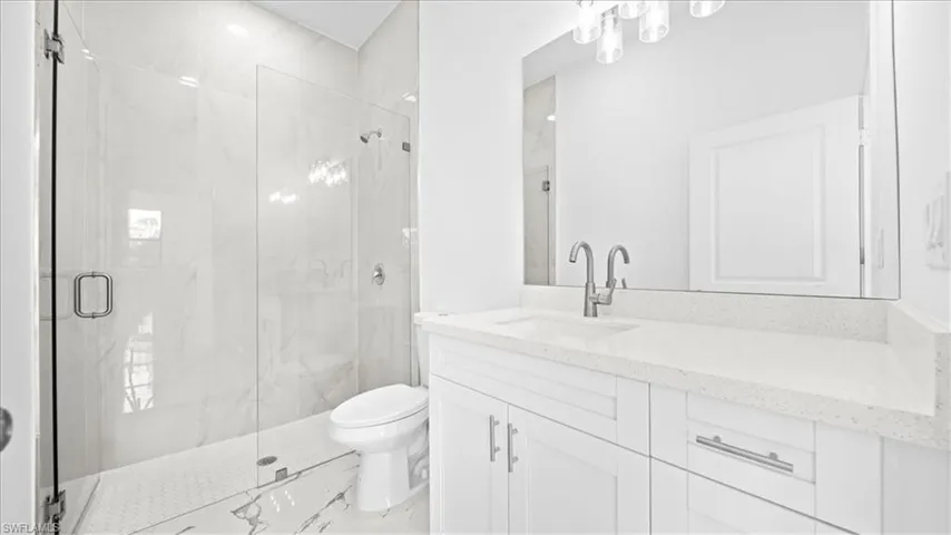 Bathroom with vanity and a marble finish shower