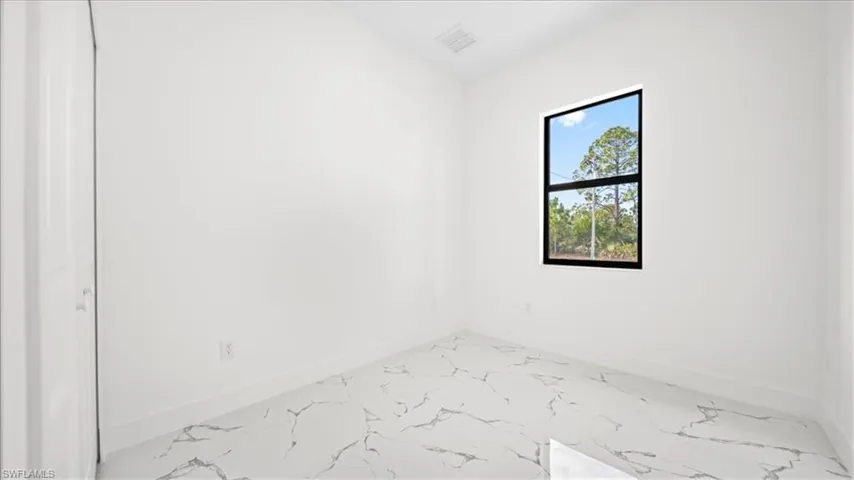 Spare room featuring baseboards and light marble finish floors