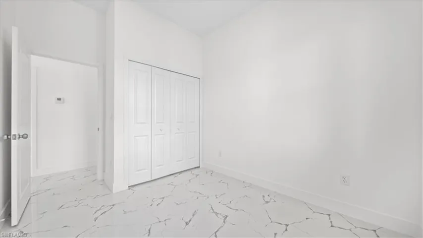 Unfurnished bedroom with light marble finish flooring and a closet
